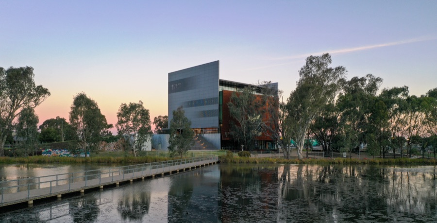 A commercial building mirrored in its reflecting pool at dusk