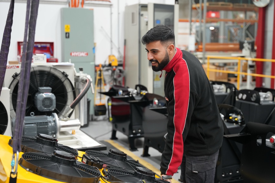 A technician working on hydraulic assemblies at the workshop bench
