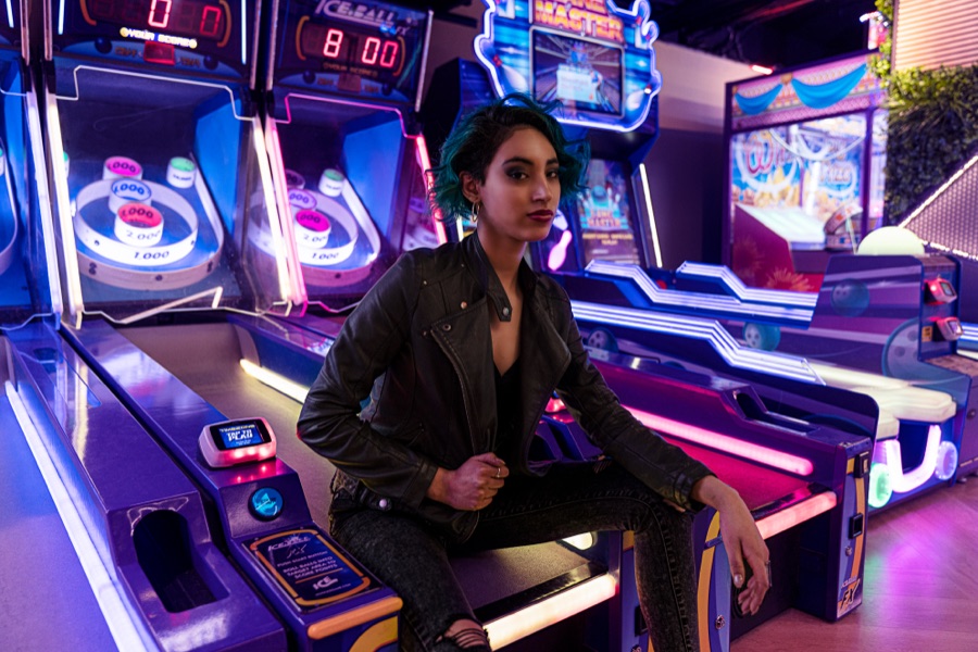 Portrait seated among the machines in a neon arcade