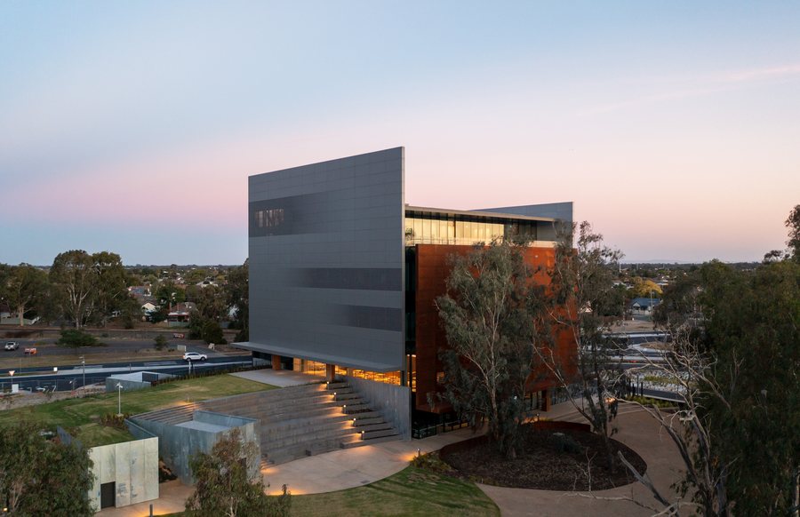 Aerial three quarter view of a corten and glass civic building at dusk