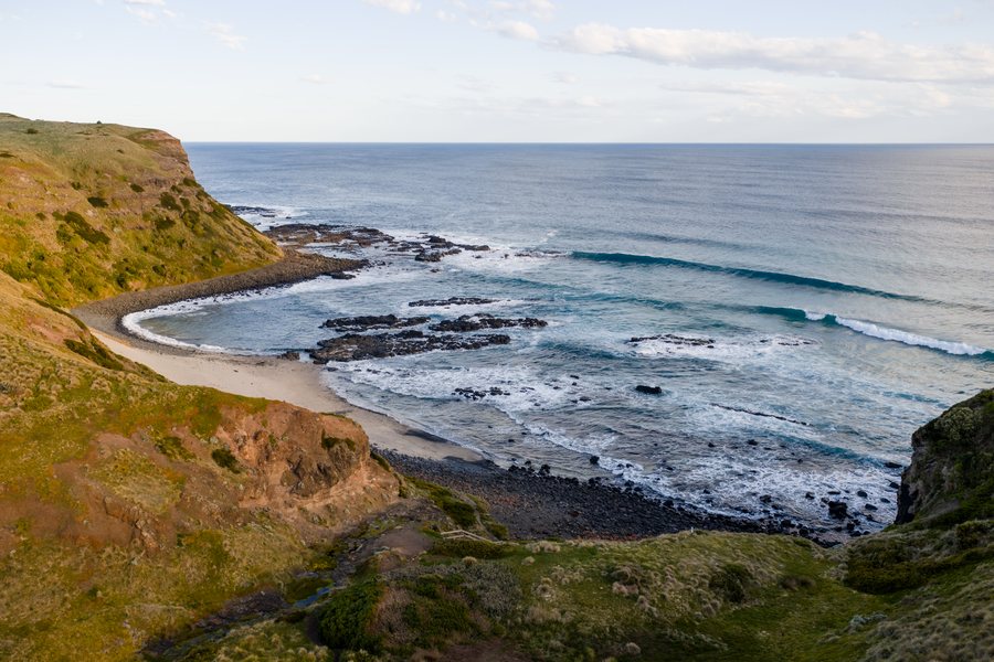 Aerial view along coastal cliffs and a curved beach on the Victorian coast