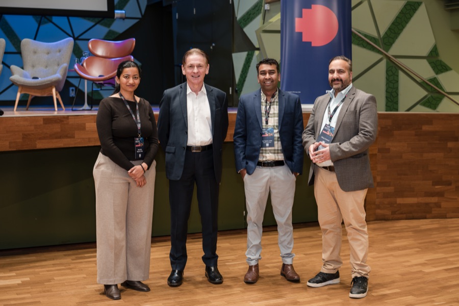 Four forum speakers together in front of the stage after their session