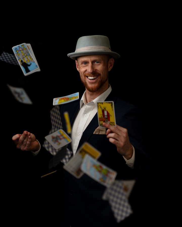 Performer throwing playing cards, lit against black