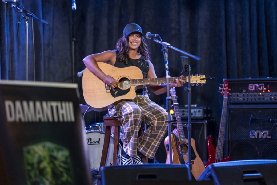 Musician performing with a guitar on a lit stage
