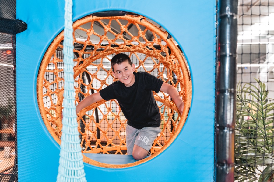 Child climbing through the rope tunnel at the Royal Pickle Club