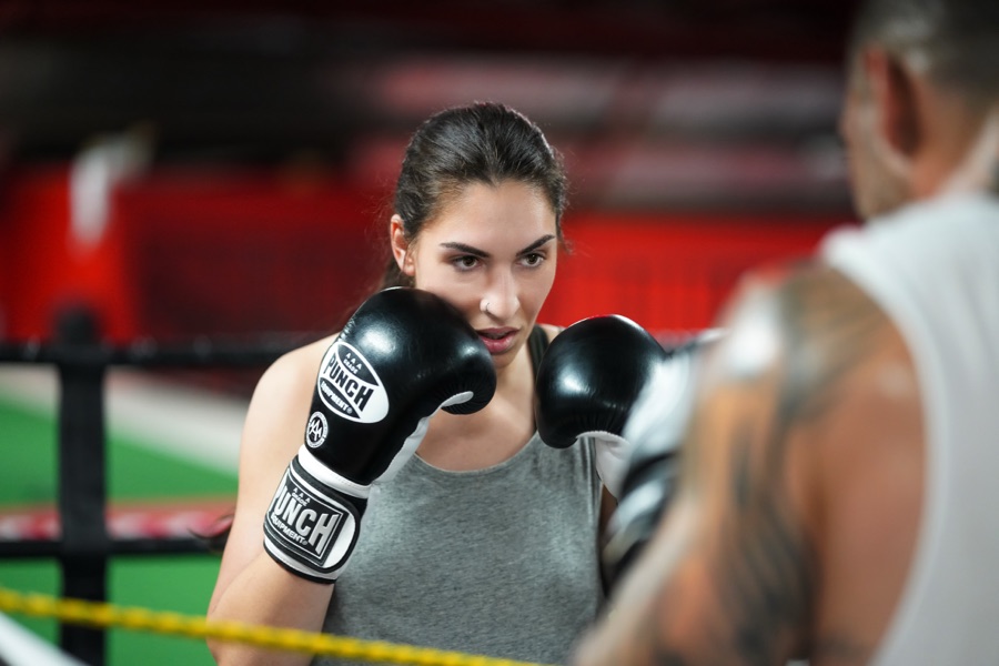 A boxer in gloves squaring up to a coach on the pads in the ring