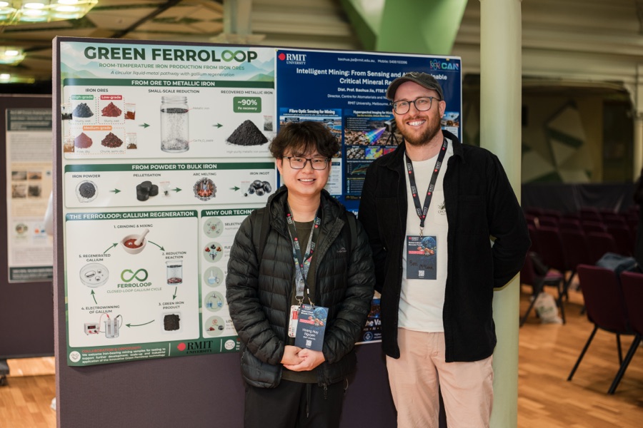 Two researchers beside the Green Ferroloop poster at the RMIT forum
