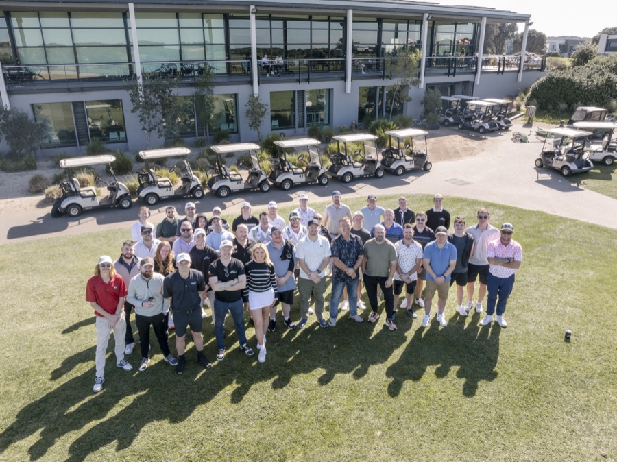 Aerial of a full field of players and buggies on a golf course