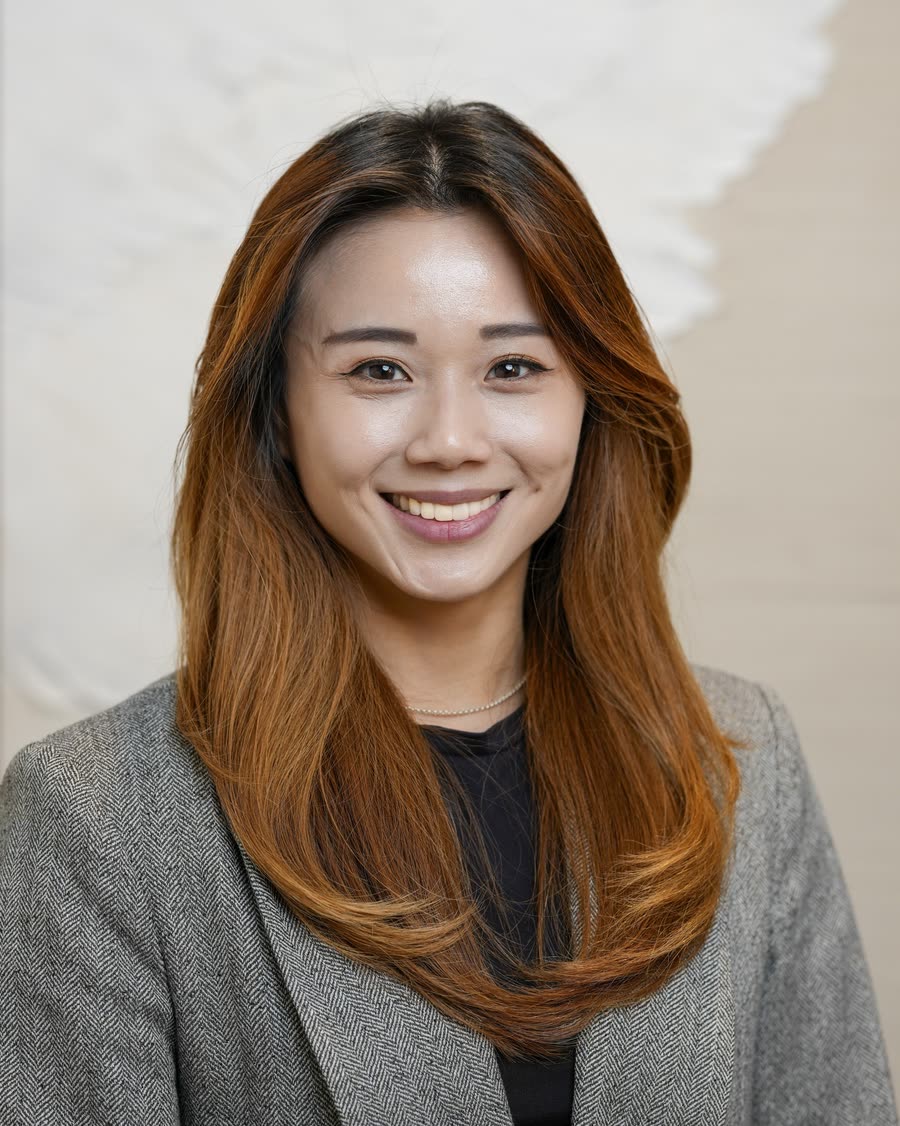 Corporate headshot of a professional in a grey blazer on a soft textured backdrop