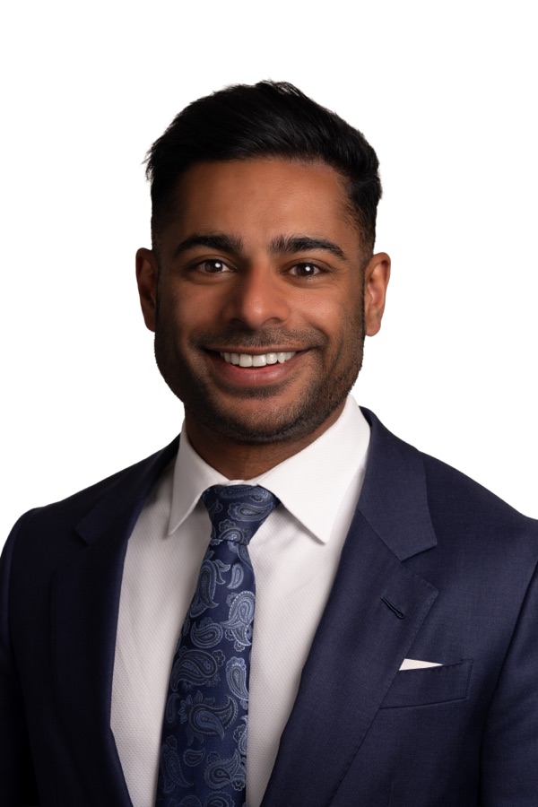 Corporate headshot of a man in a navy suit and patterned tie