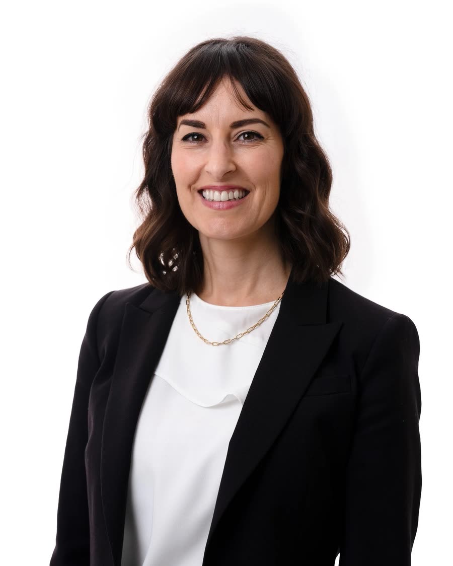 Studio headshot of a professional in a black blazer on a white background