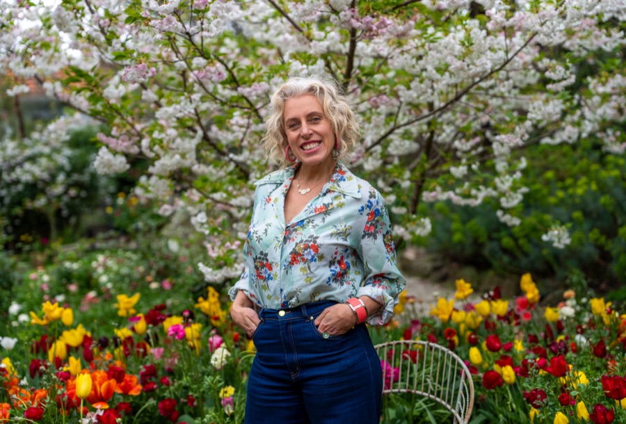 Portrait of a woman in a floral shirt among spring blossom and tulips