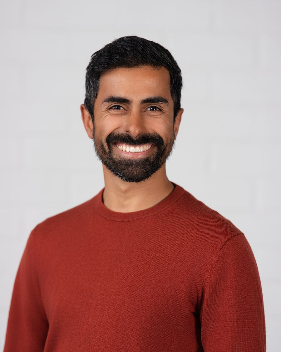 Headshot of a man in a rust knit on a clean white ground