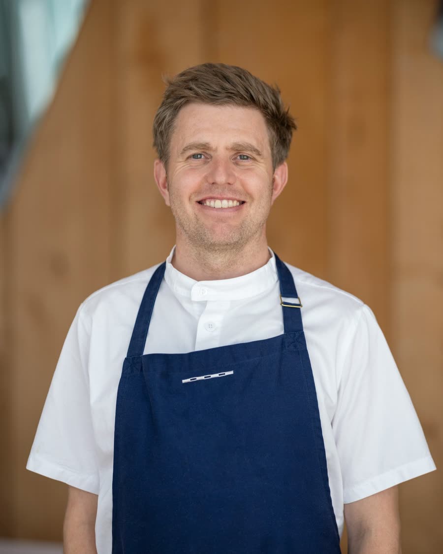On-location headshot of a chef in whites and a navy apron