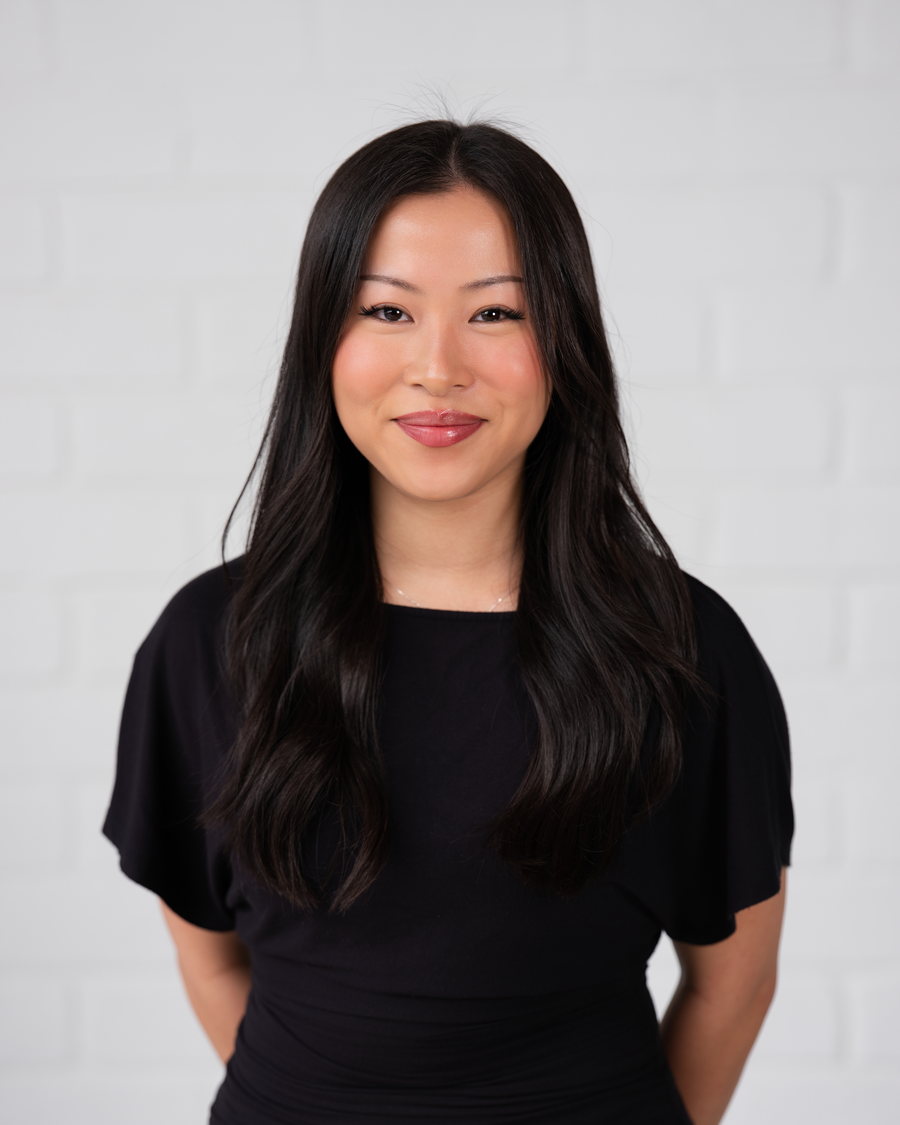 Headshot of a woman in black against a white brick wall