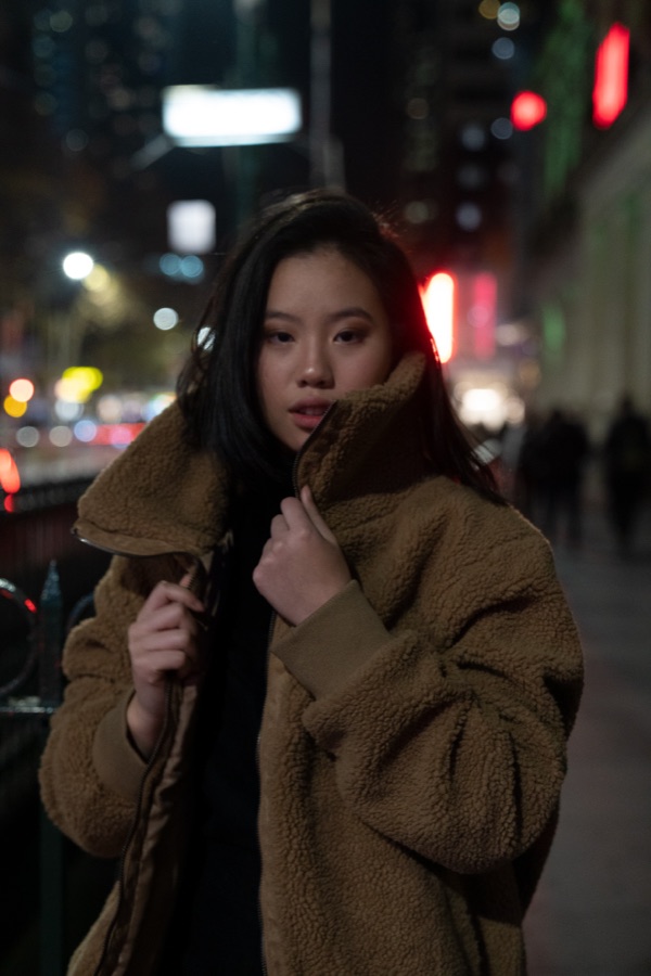 Woman in a winter coat on a city street at night