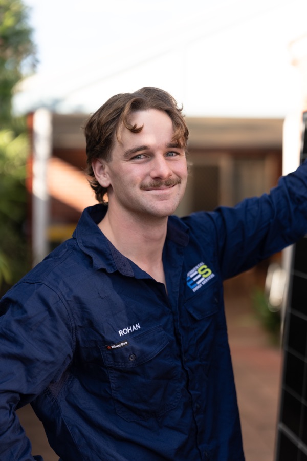 Tradesman in branded workwear reaching up on site