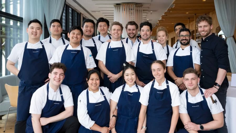 A hospitality team in aprons photographed together in their venue, Melbourne