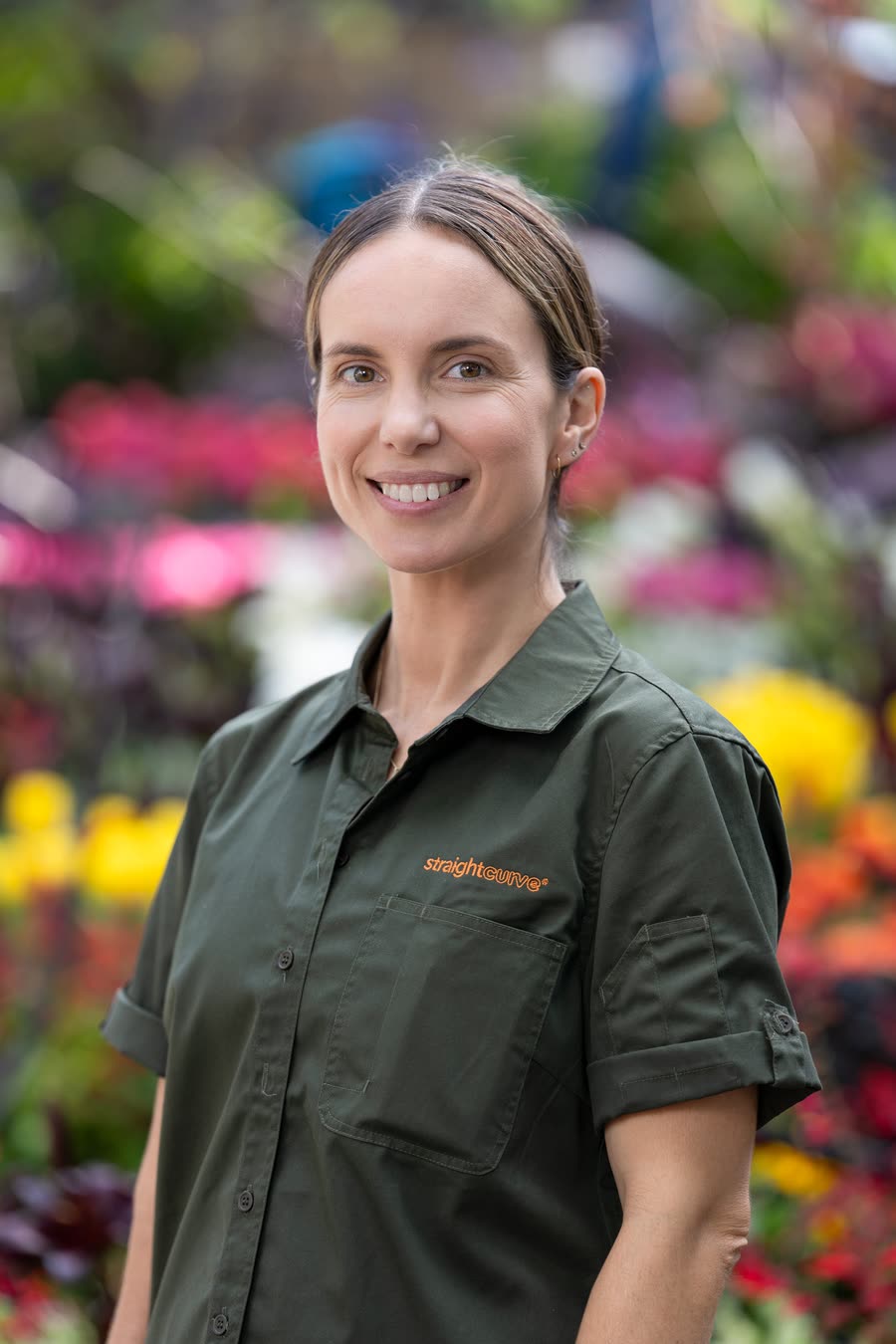 On-location headshot of a nursery team member in a branded shirt among flowering stock