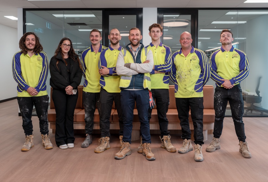 A glazing team of eight photographed together in branded workwear