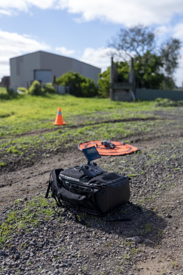 Drone case and controller set up on gravel beside a farm shed