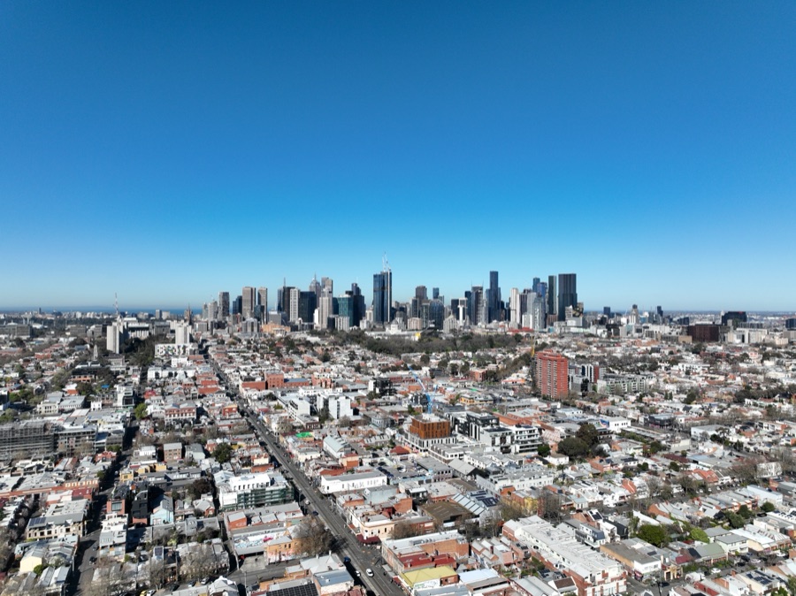 Aerial over the city grid to the towers beyond
