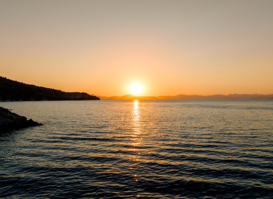 Sun setting over the ocean beyond a headland