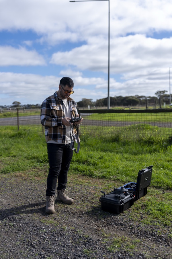 Operator in a paddock beside a drone case before a flight