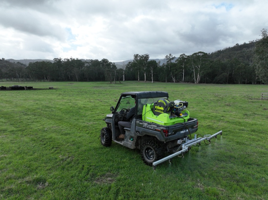 A utility vehicle parked on cleared pasture under heavy cloud