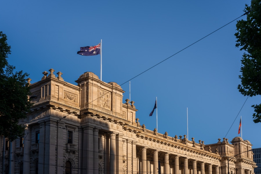 Parliament House and its flags against a clear sky