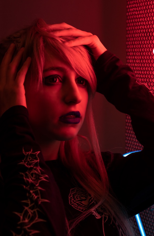 A portrait lit entirely in red against a perforated wall