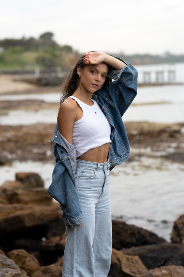 A portrait on the rocks at the water's edge in a denim jacket