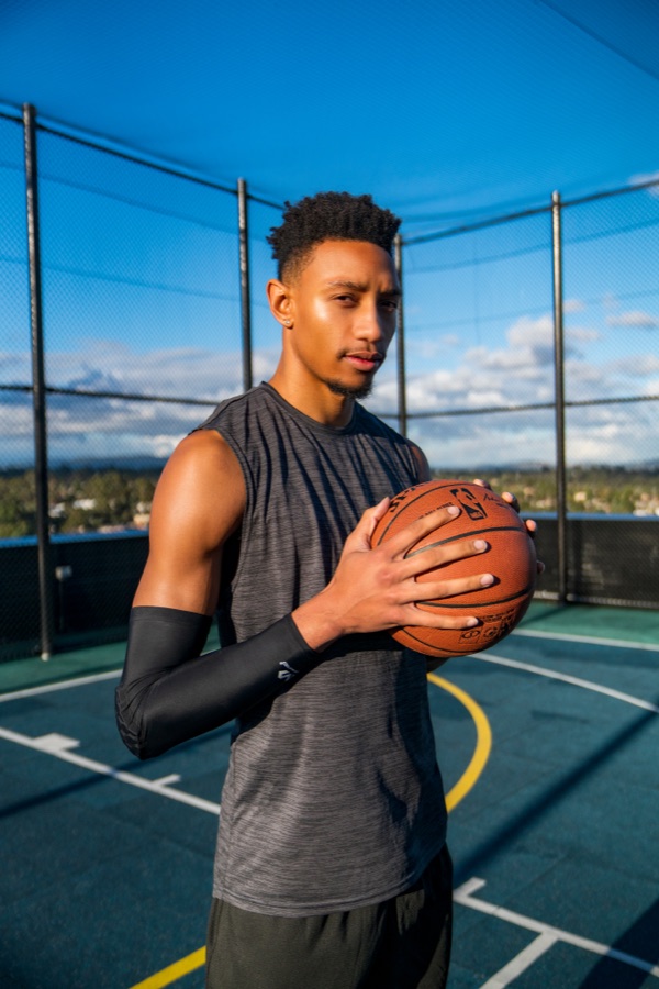 Basketball player holding a ball on an outdoor court beneath open sky