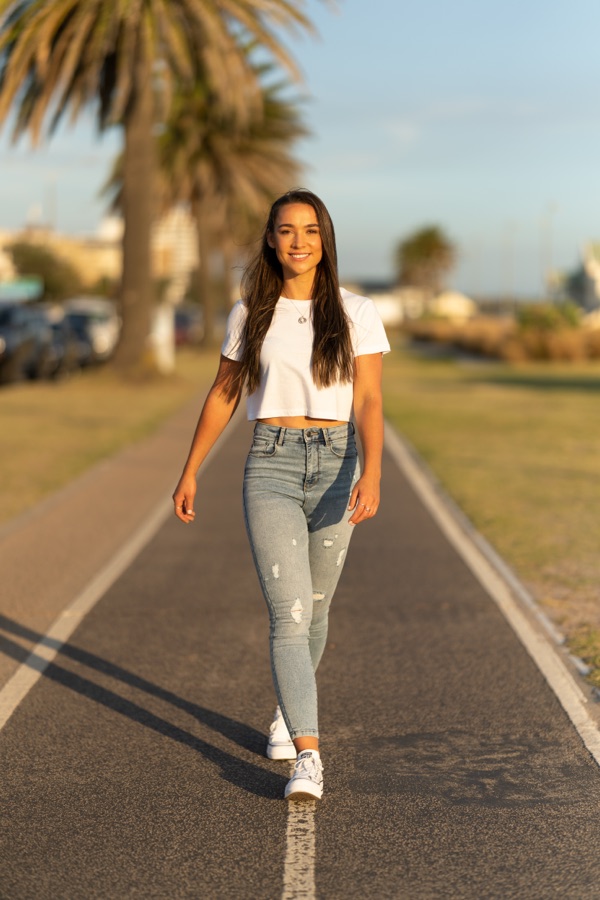A woman walking a palm lined path toward the camera