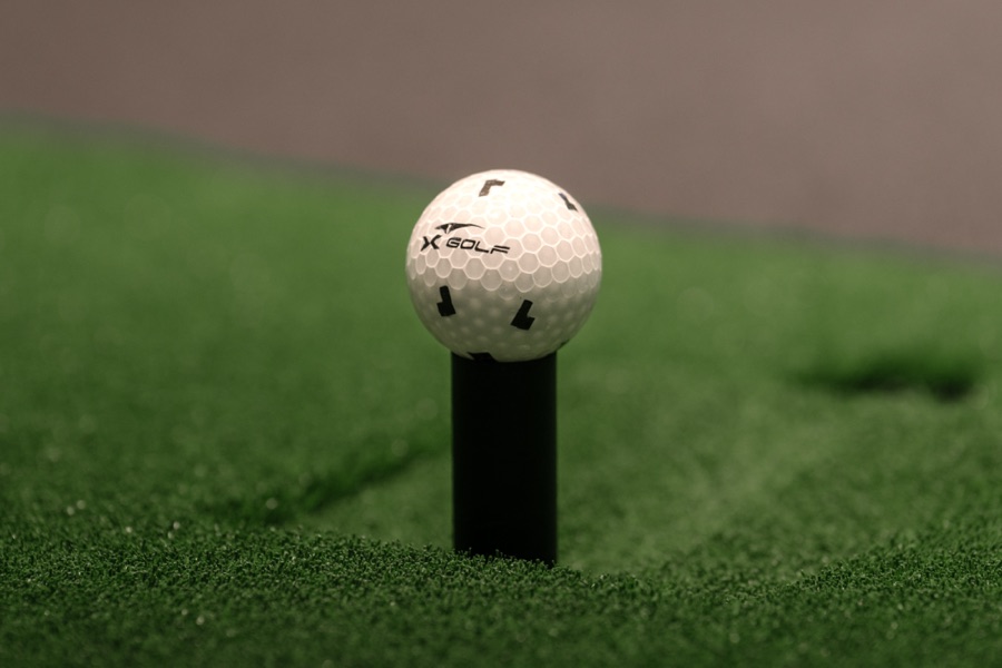 A golf ball on a tee, photographed low against the grass