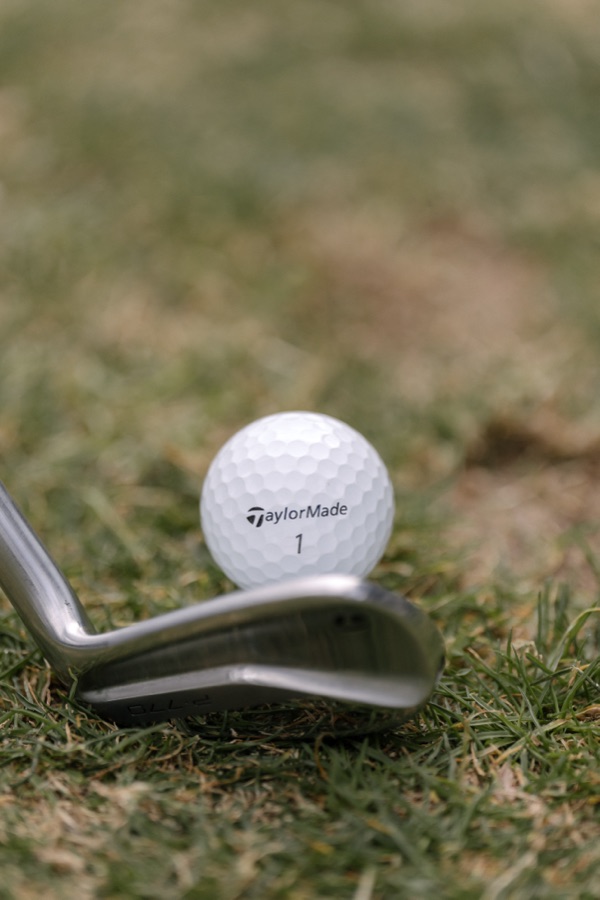 Close detail of a golf club head resting behind the ball