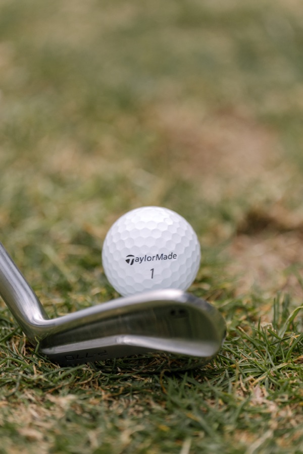 A golf club head resting behind a ball on the grass