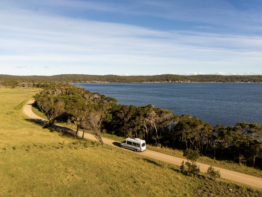 A campervan on a coastal track above a sheltered bay in Tasmania
