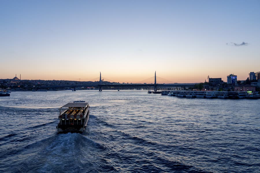A ferry crossing the Bosphorus at dusk with the Istanbul skyline beyond